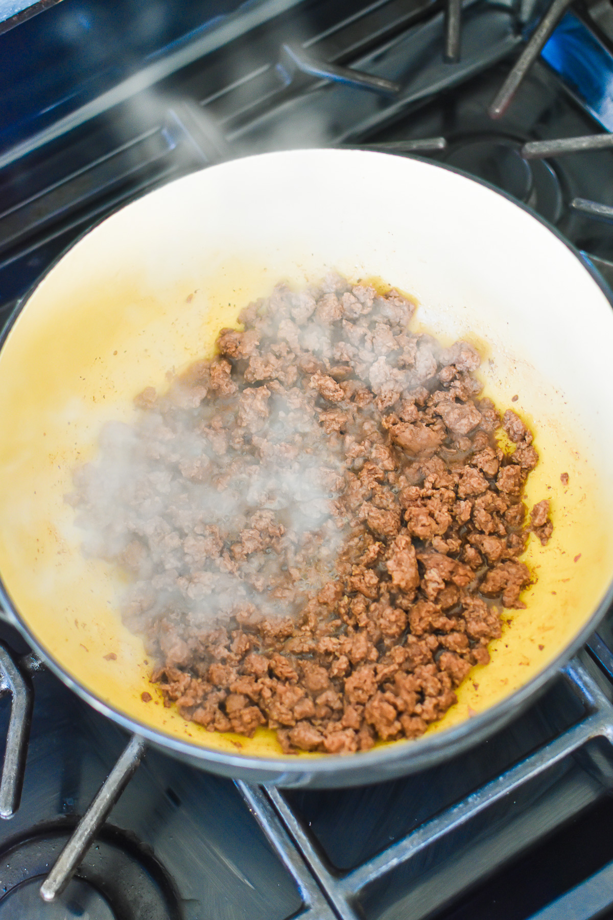 browned ground beef in black dutch oven on stove top.
