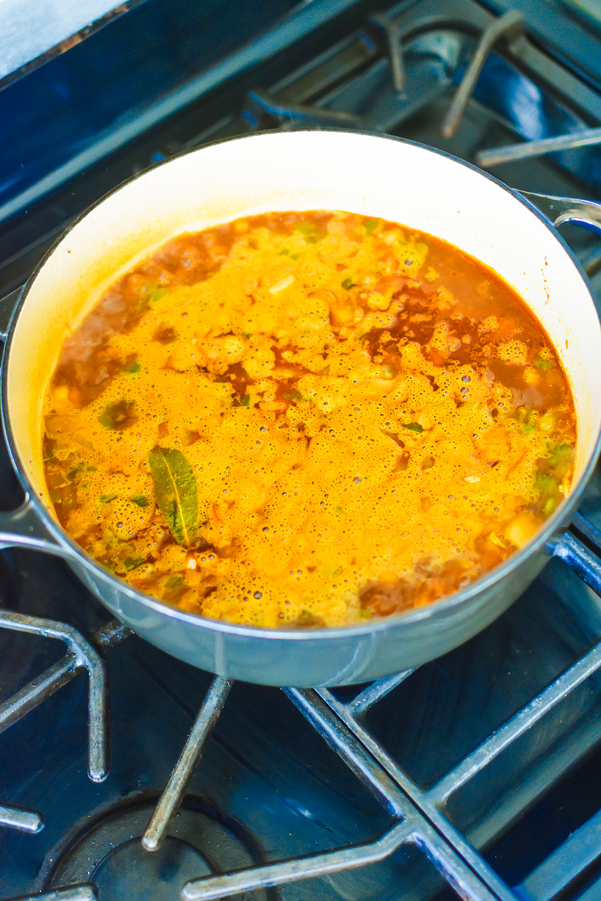 bubbling pot of pinto beans and aromatics in beef broth.
