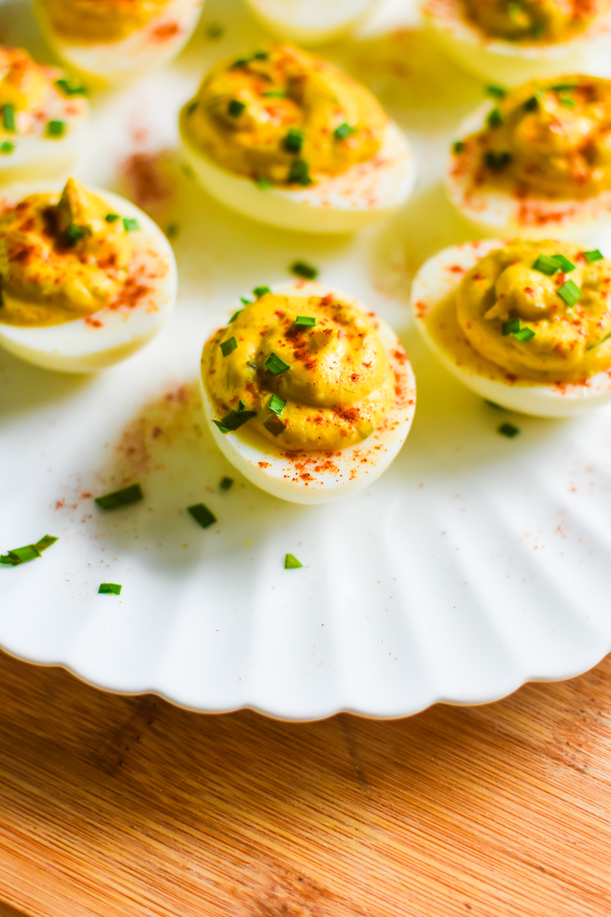 platter of black deviled eggs topped with herbs and spices.