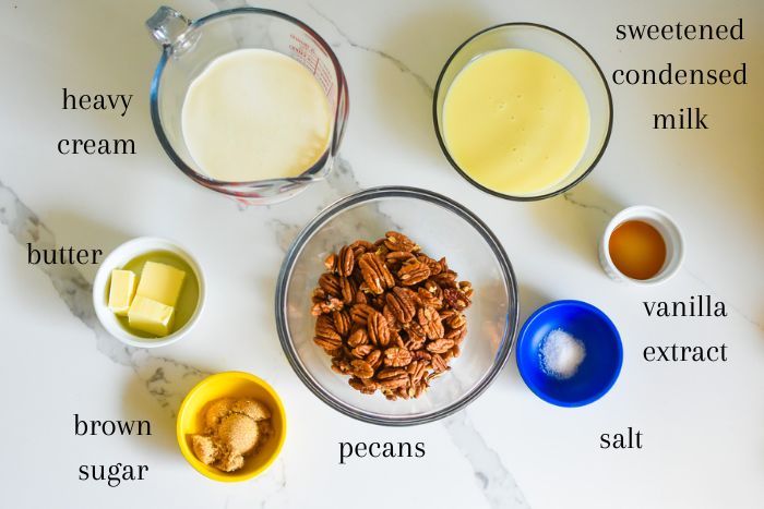 homemade butter pecan ice cream ingredients on granite counter top: heavy cream, sweetened condensed milk, butter, vanilla extract, pecans, salt, and brown sugar.