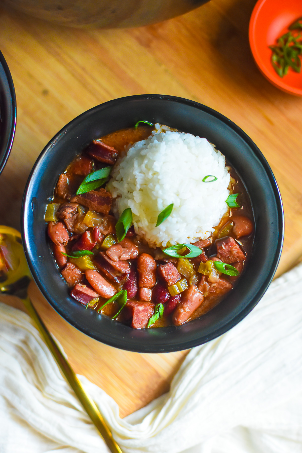 the best red beans and rice made from scratch and served in a black ceramic bowl with sliced scallions over top.