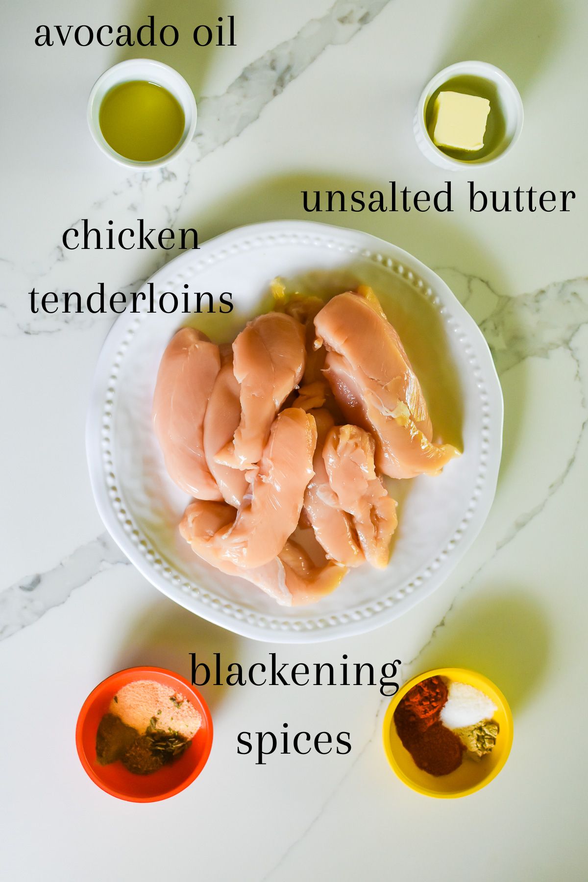 ingredients for blackened chicken strips at home: avocado oil, unsalted butter, raw chicken tenderloins, and traditional blackened spices.