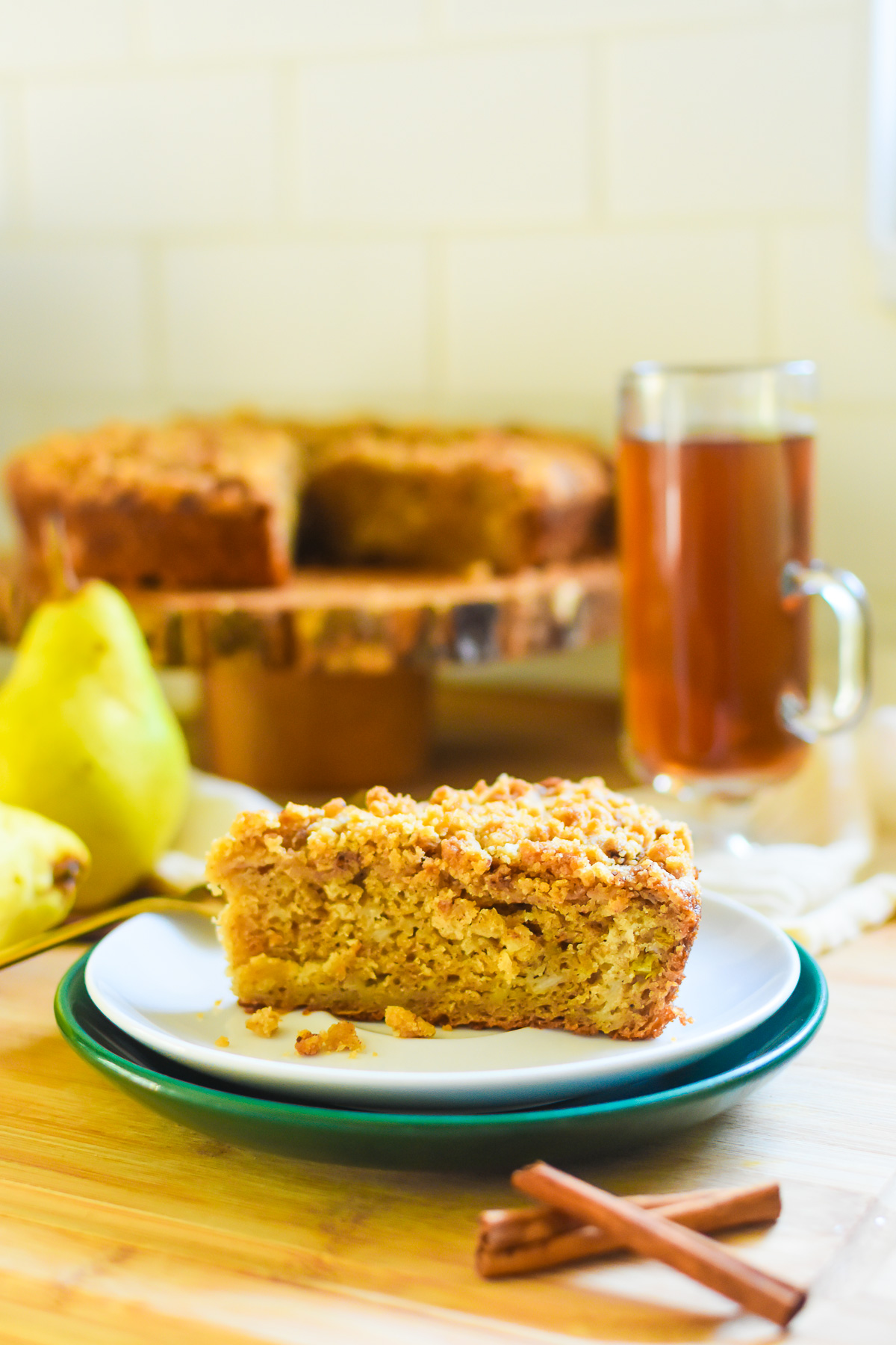 slice of the best pear cake with a Dutch crumble topping served on a stack of white and green saucers.