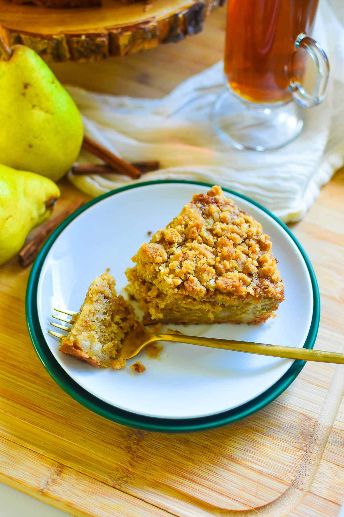 slice of pear cake with warm spices and brown sugar crumb on plate with a gold fork.